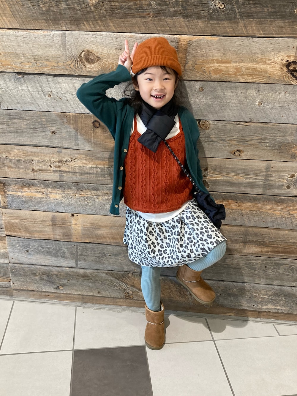 グリーン系のショルダーバッグ、グリーン系のカーディガン/ボレロ、ベージュ系のスカートを着用したキッズの冬コーディネートの2枚目の写真