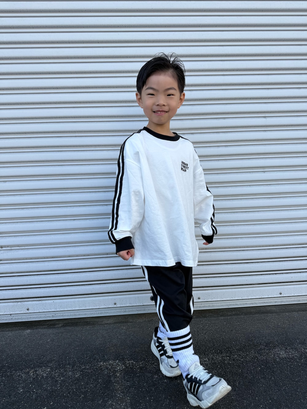 ホワイト系のTシャツ/カットソー、ブラック系のその他パンツ、ホワイト系のスニーカーを着用したキッズの春コーディネートの3枚目の写真