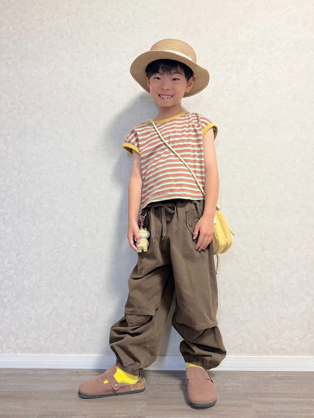 ブラウン系のTシャツ/カットソー、ブラウン系のカーゴパンツ、イエロー系のショルダーバッグを着用したキッズの夏コーディネートの3枚目の写真