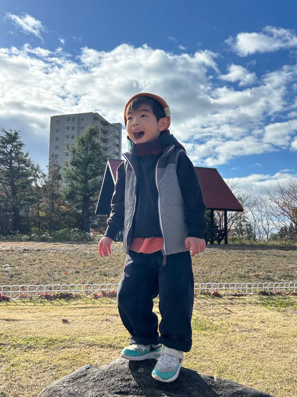 オレンジ系のスウェット、グレー系のスウェット、グレー系のダウンベストを着用したキッズの冬コーディネートの2枚目の写真