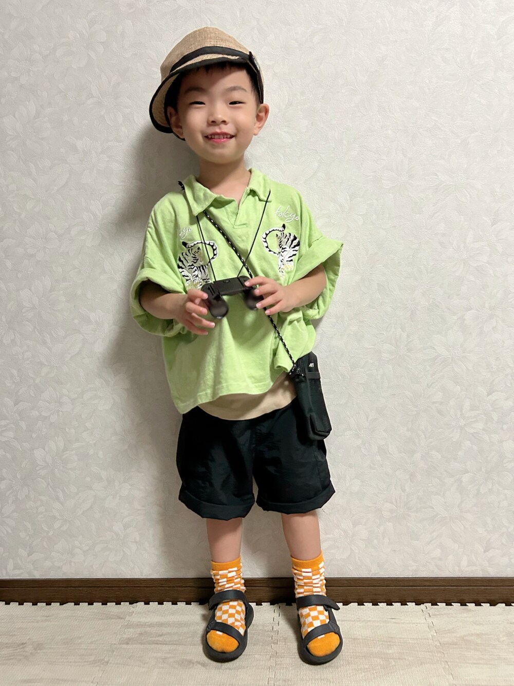 ベージュ系のタンクトップ、グリーン系のポロシャツ、ブラック系のカーゴパンツを着用したキッズの夏コーディネートの3枚目の写真