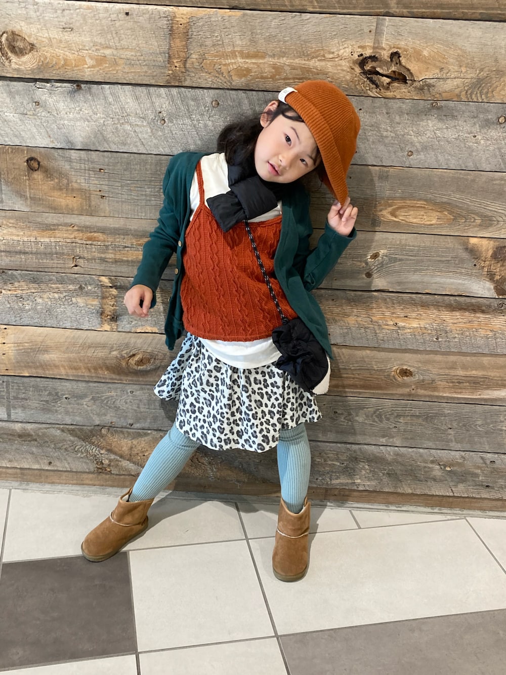 グリーン系のショルダーバッグ、グリーン系のカーディガン/ボレロ、ベージュ系のスカートを着用したキッズの冬コーディネートの3枚目の写真