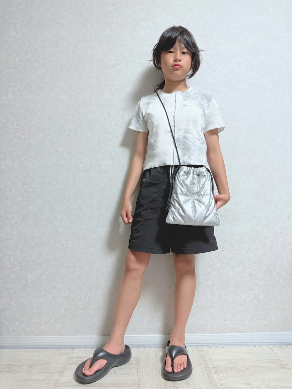シルバー系のショルダーバッグ、グレー系のTシャツ/カットソー、ブラック系のパンツを着用したキッズの夏コーディネートの2枚目の写真