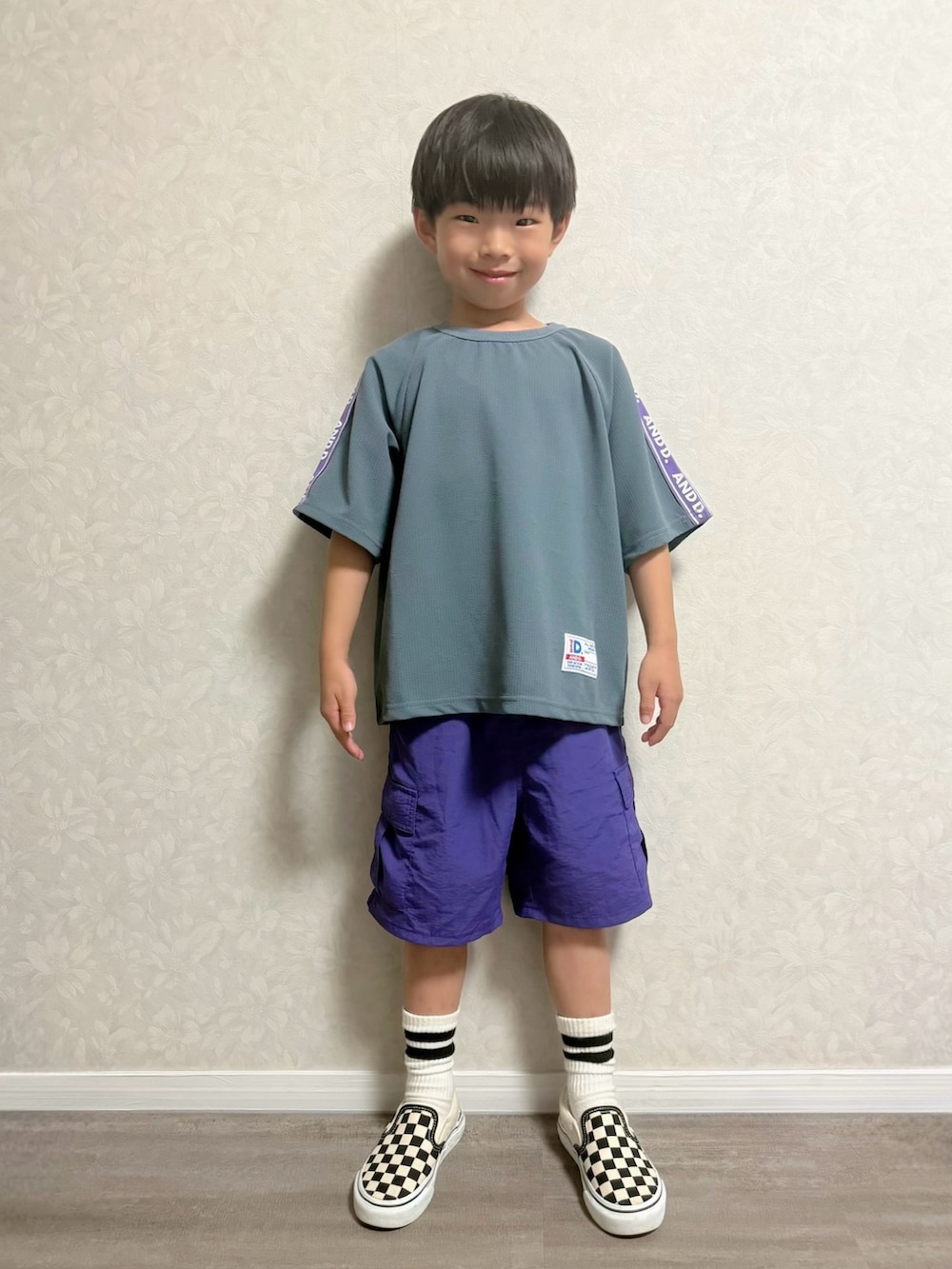 ブルー系のセットアップ、パープル系のカーゴパンツ、ブラック系のスリッポンを着用したキッズの夏コーディネートの3枚目の写真