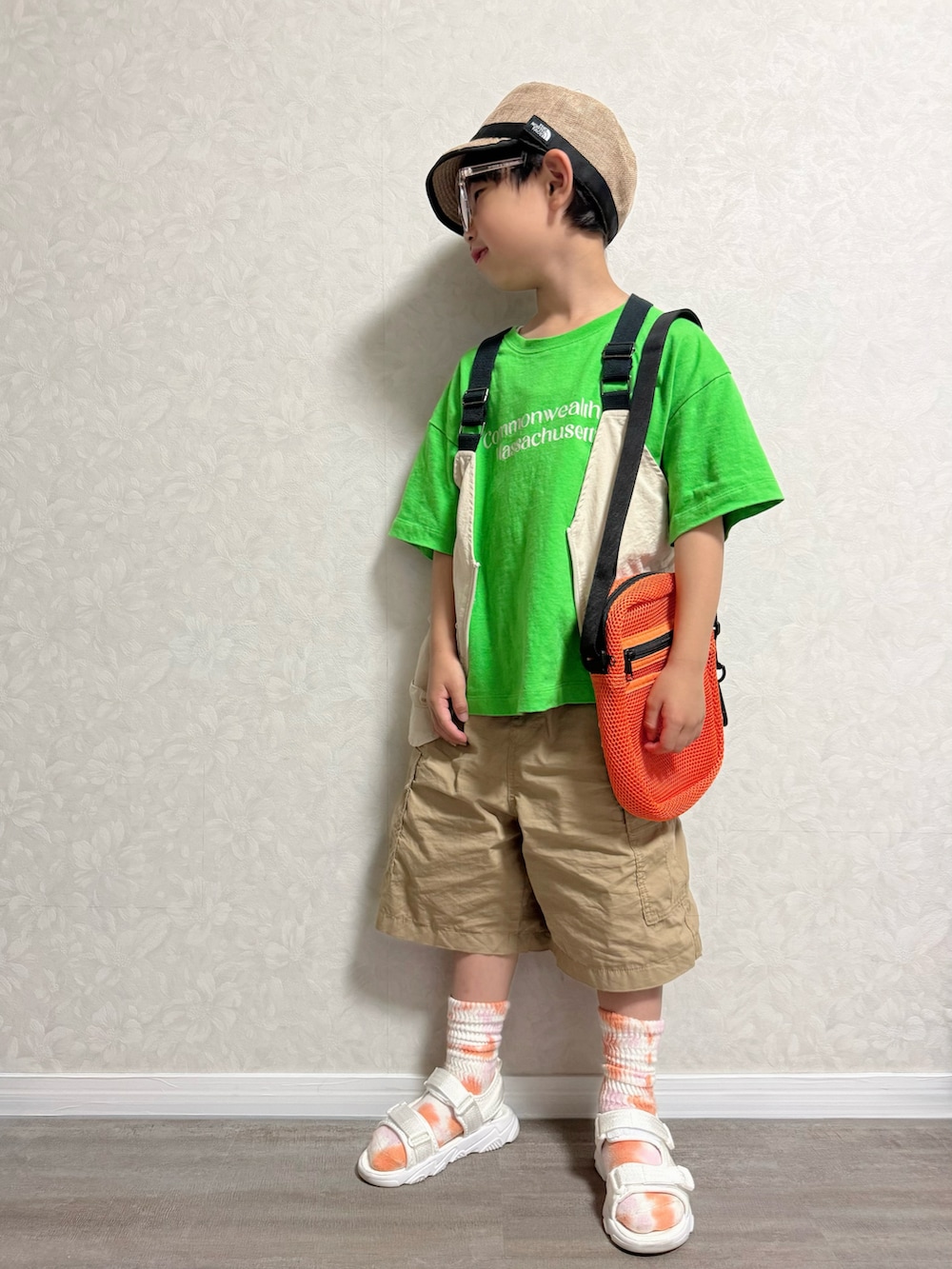 グリーン系のTシャツ/カットソー、ベージュ系のベスト、オレンジ系のショルダーバッグを着用したキッズの春コーディネートの2枚目の写真