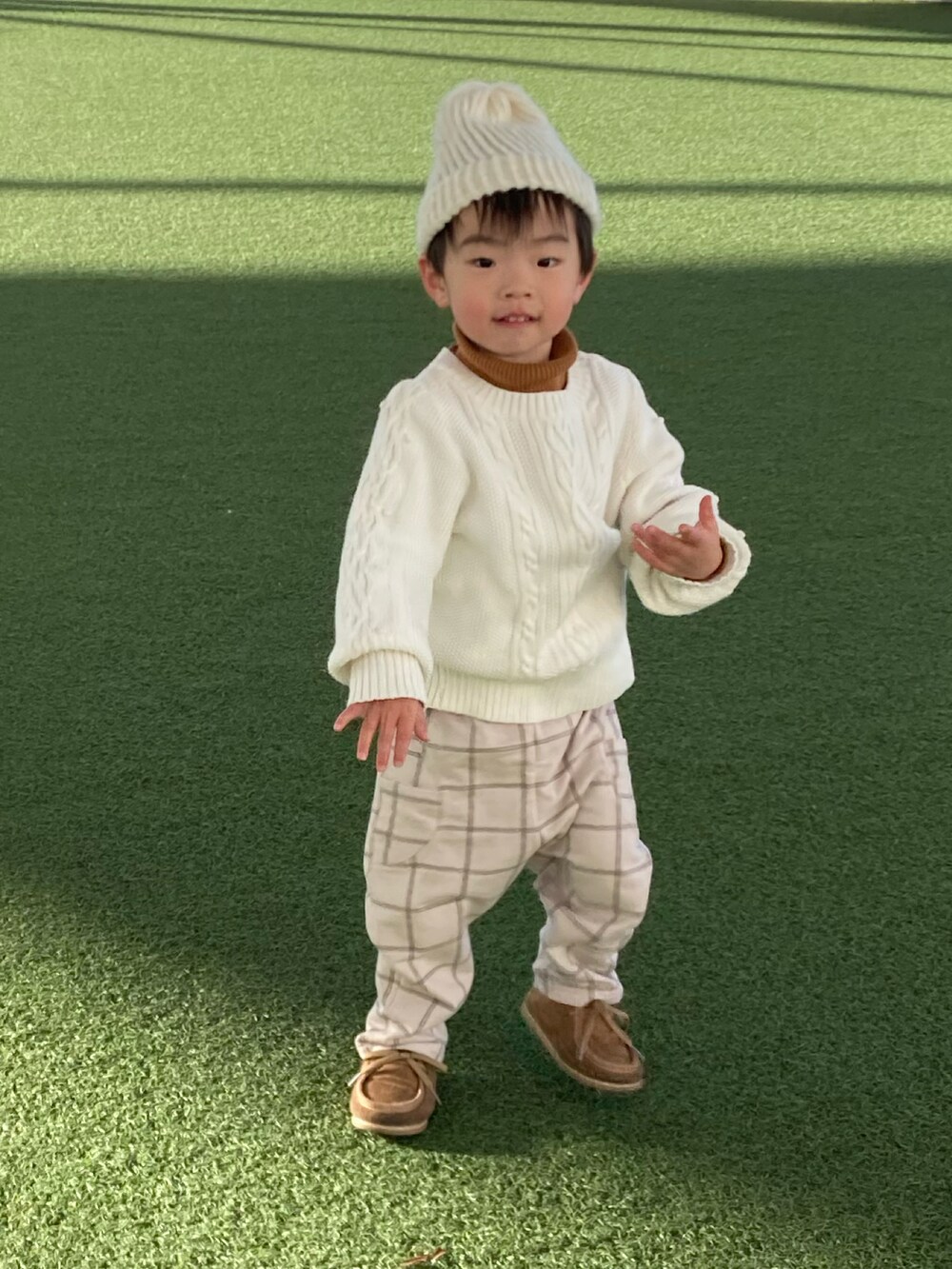 ホワイト系のニット/セーター、ブラウン系のショルダーバッグ、ベージュ系のパンツを着用したキッズの冬コーディネートの4枚目の写真