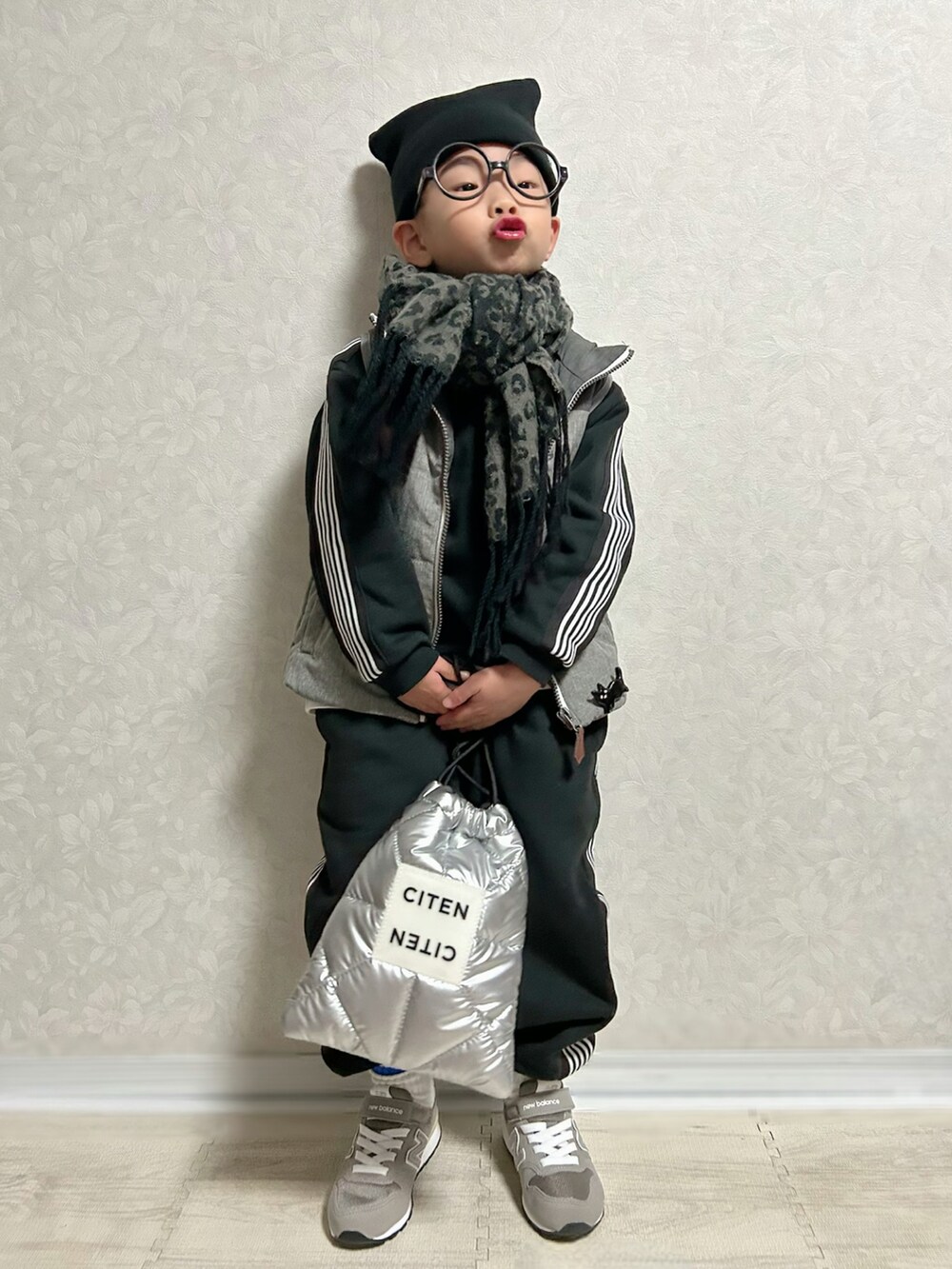 ホワイト系のTシャツ/カットソー、ブラック系のセットアップ、グレー系のダウンベストを着用したキッズの冬コーディネートの2枚目の写真