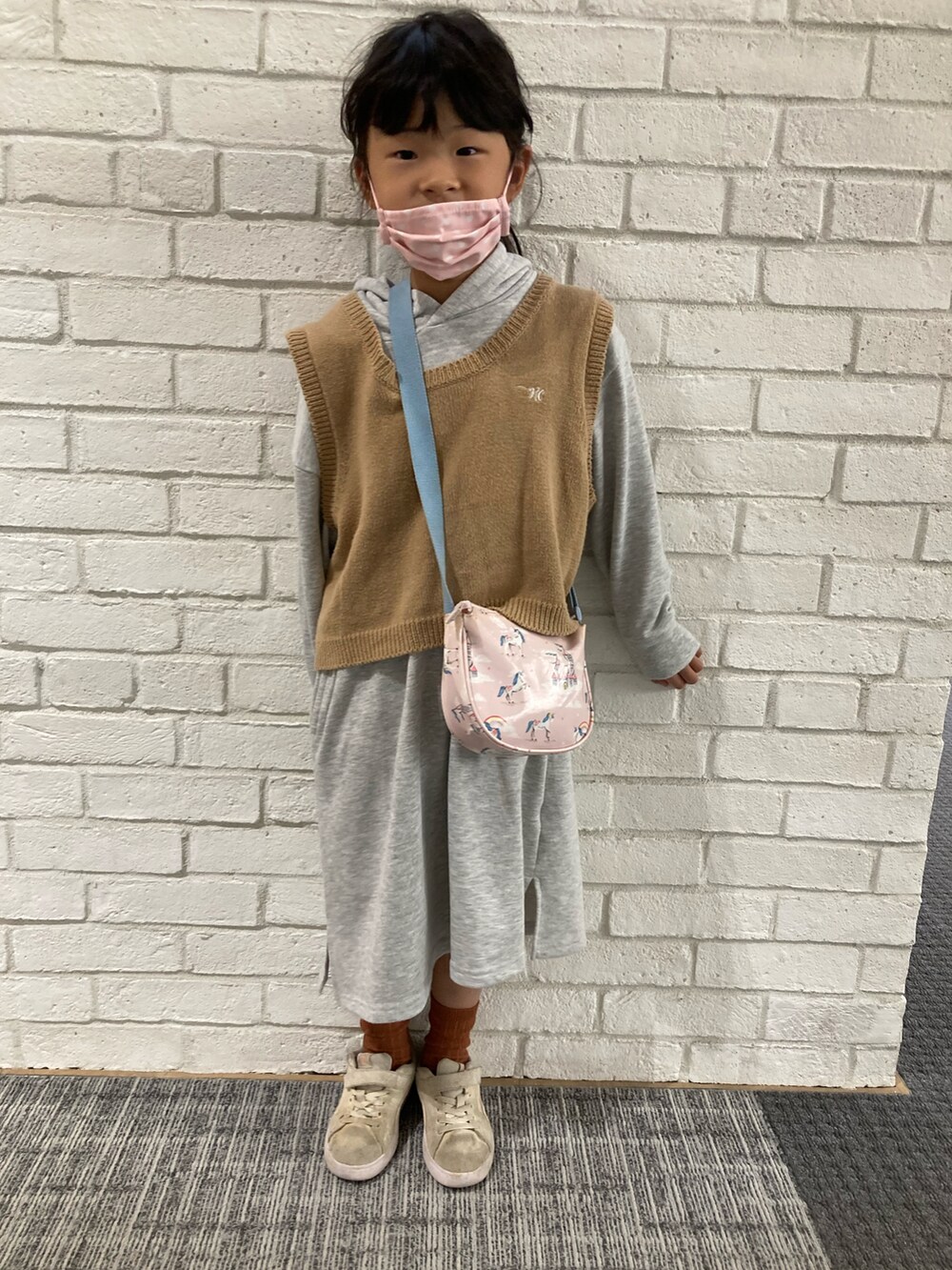 グレー系のワンピース、ベージュ系のベスト、ピンク系のショルダーバッグを着用したキッズの秋コーディネートの2枚目の写真