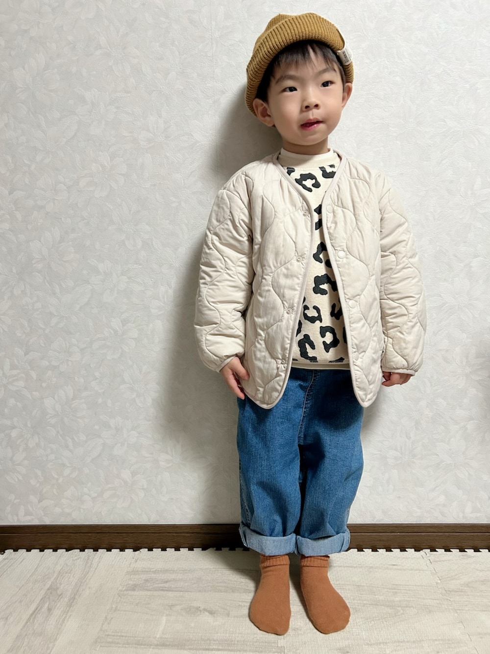 ベージュ系のスウェット、ホワイト系のノーカラージャケット、ブルー系のデニムパンツを着用したキッズの冬コーディネートの2枚目の写真