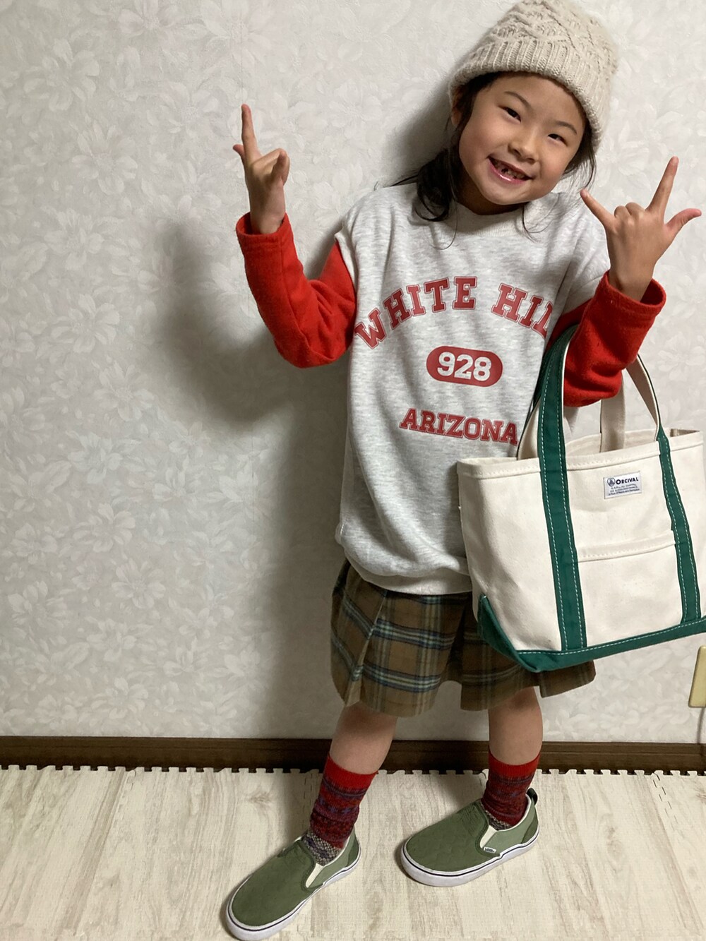 グレー系のベスト、ブラウン系のスカート、グリーン系のトートバッグを着用したキッズの冬コーディネートの3枚目の写真