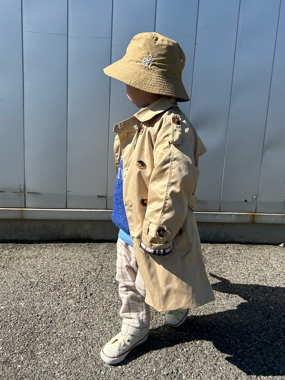 ベージュ系のトレンチコート、ブルー系のニット/セーター、ブルー系のTシャツ/カットソーを着用したキッズの冬コーディネートの4枚目の写真