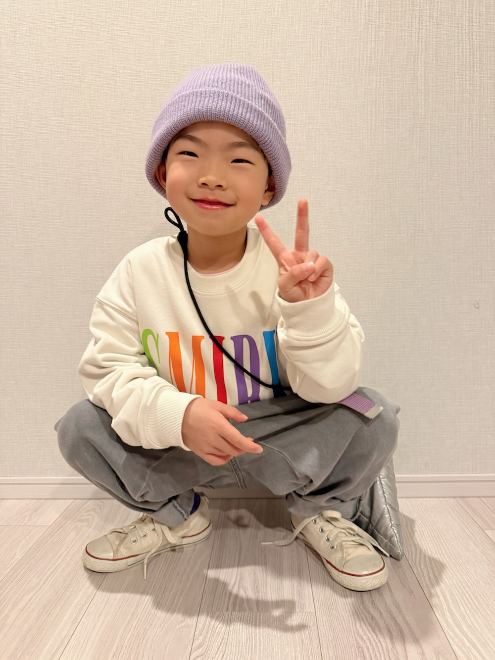 ホワイト系のスウェット、ホワイト系のスニーカー、シルバー系のショルダーバッグを着用したキッズの冬コーディネートの3枚目の写真