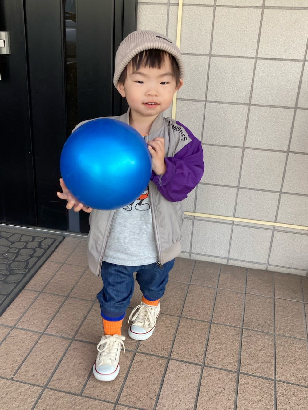 オレンジ系のタンクトップ、グレー系のTシャツ/カットソー、グレー系のナイロンジャケットを着用したキッズの春コーディネートの4枚目の写真