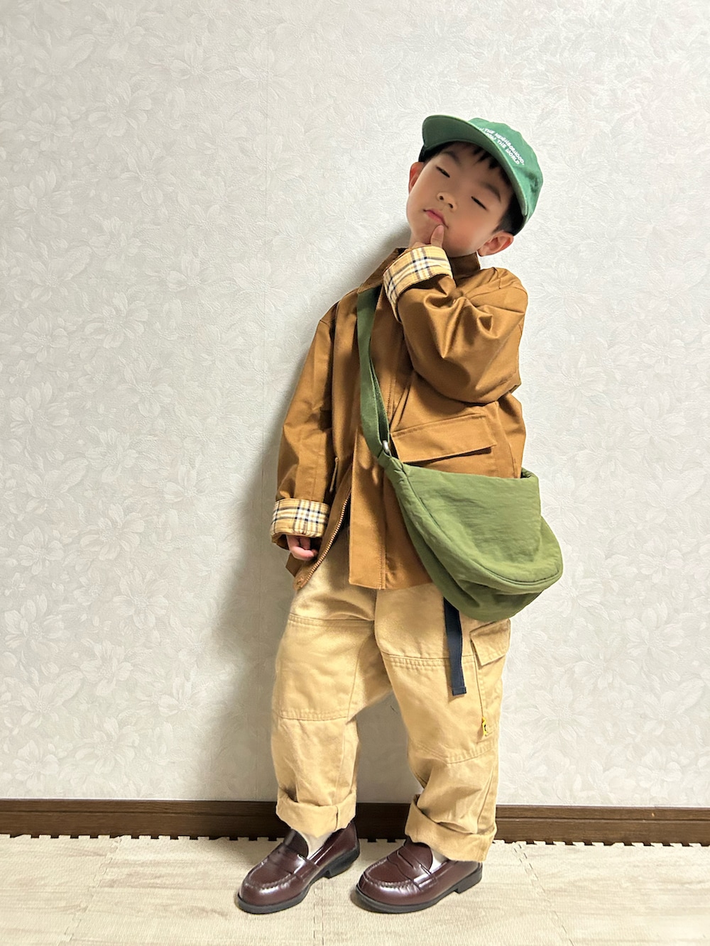 ブラウン系のブルゾン、グリーン系のショルダーバッグ、オレンジ系のTシャツ/カットソーを着用したキッズの秋コーディネートの4枚目の写真