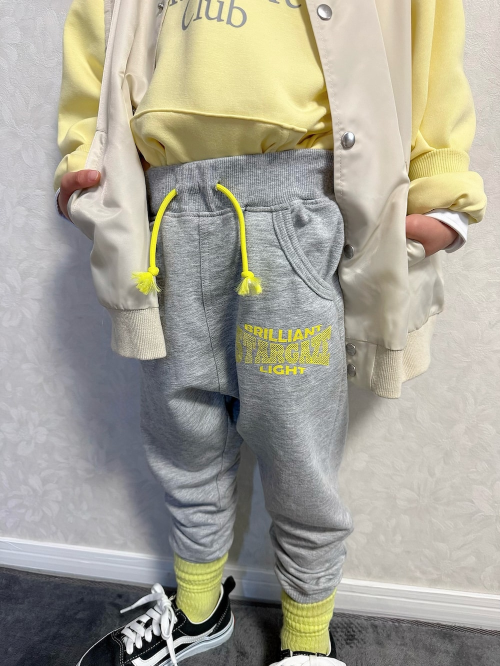 ベージュ系のベスト、グレー系のスウェットパンツ、シルバー系のショルダーバッグを着用したキッズの冬コーディネートの5枚目の写真