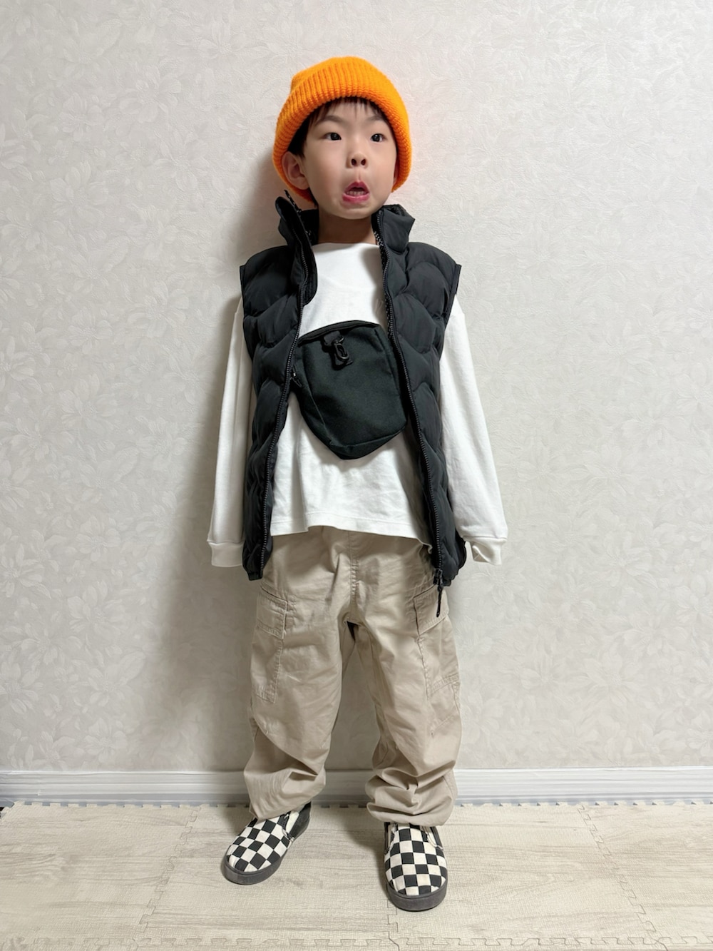 ホワイト系のTシャツ/カットソー、ブラック系のダウンベスト、ベージュ系のカーゴパンツを着用したキッズの春コーディネートの3枚目の写真