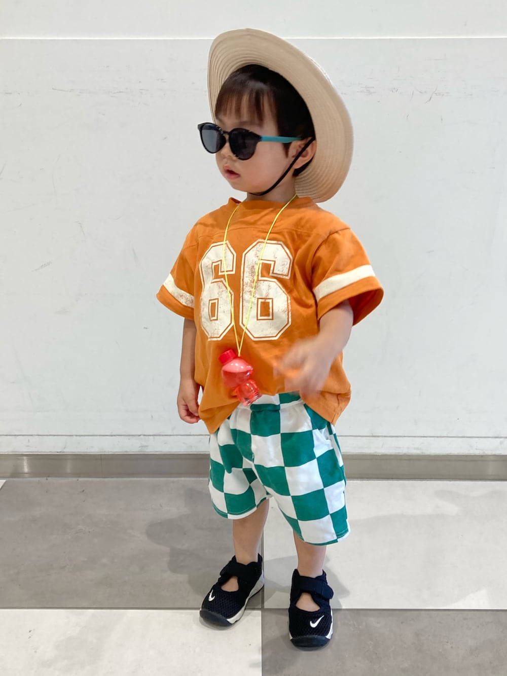 オレンジ系のTシャツ/カットソー、グリーン系のパンツ、ブラック系のサンダルを着用したキッズの夏コーディネートの2枚目の写真