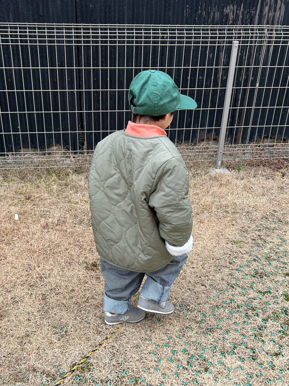 オレンジ系のスウェット、グリーン系のノーカラージャケット、ブルー系のデニムパンツを着用したキッズの冬コーディネートの3枚目の写真