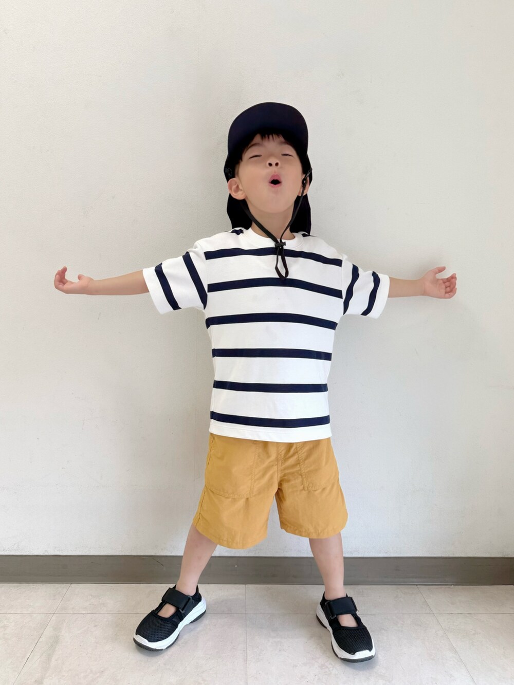 ブラック系のサンダル、ホワイト系のTシャツ/カットソー、ベージュ系のパンツを着用したキッズの夏コーディネートの3枚目の写真