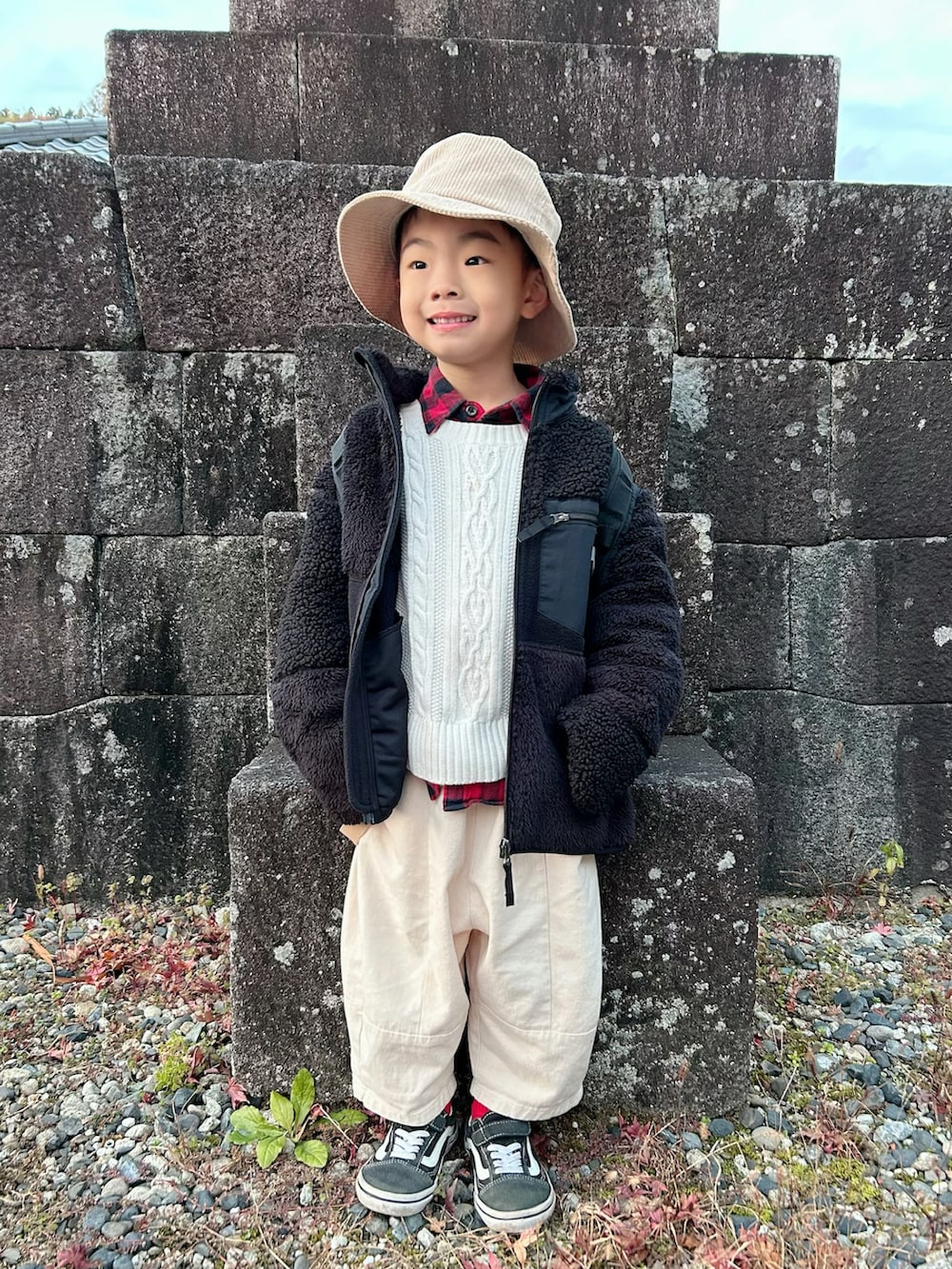 ベージュ系のチノパンツ、ブラック系のバックパック/リュック、ブラック系のスニーカーを着用したキッズの冬コーディネートの4枚目の写真