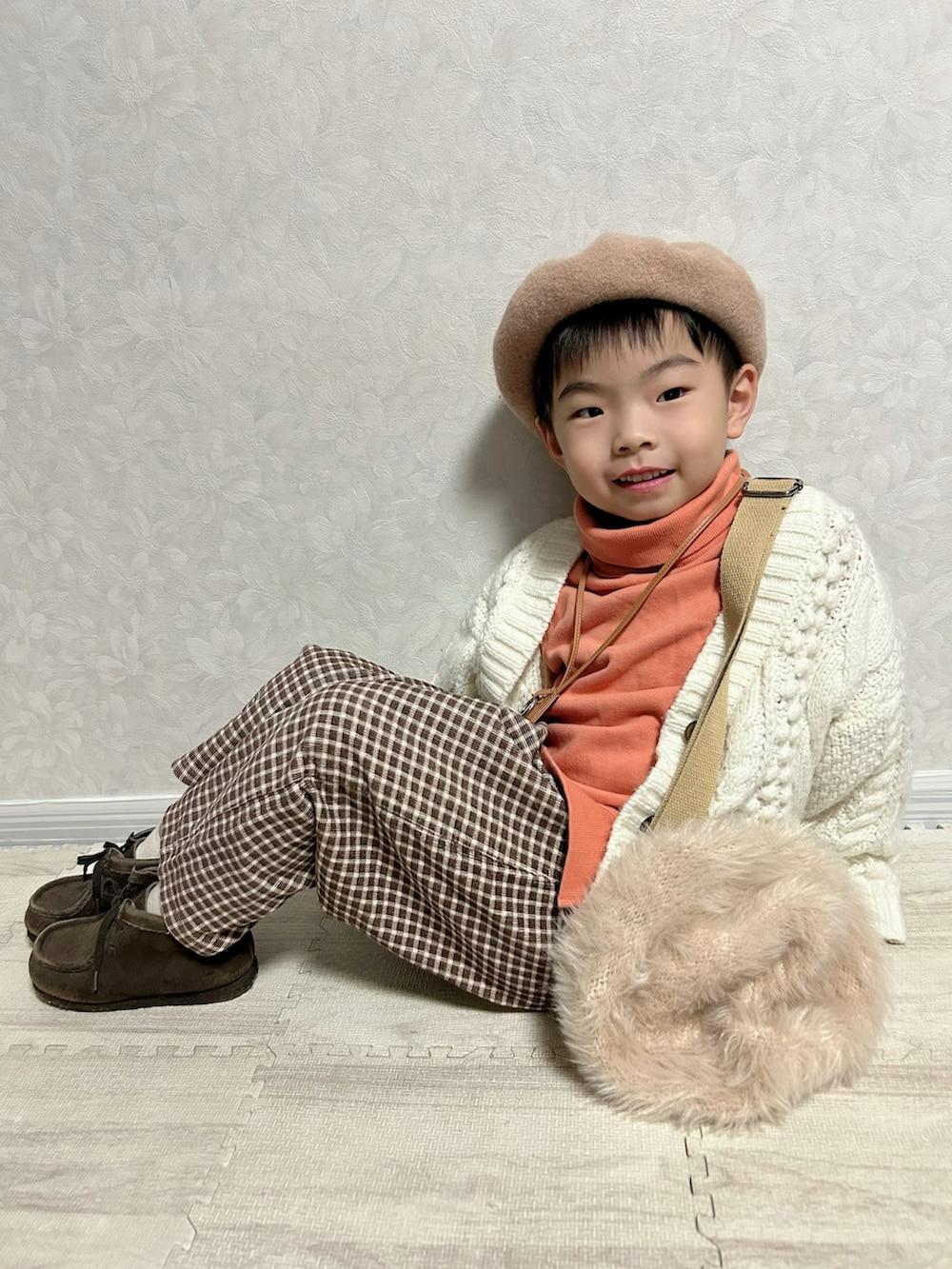 オレンジ系のスウェット、ホワイト系のカーディガン/ボレロ、ブラウン系のショルダーバッグを着用したキッズの冬コーディネートの3枚目の写真