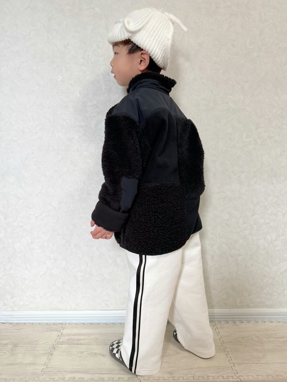 ブラック系のジャケット/アウター、グリーン系のTシャツ/カットソー、ホワイト系のスウェットパンツを着用したキッズの冬コーディネートの3枚目の写真