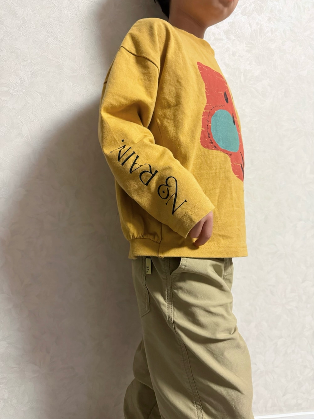 イエロー系のTシャツ/カットソー、ベージュ系のその他パンツ、ブラック系のスニーカーを着用したキッズの冬コーディネートの4枚目の写真