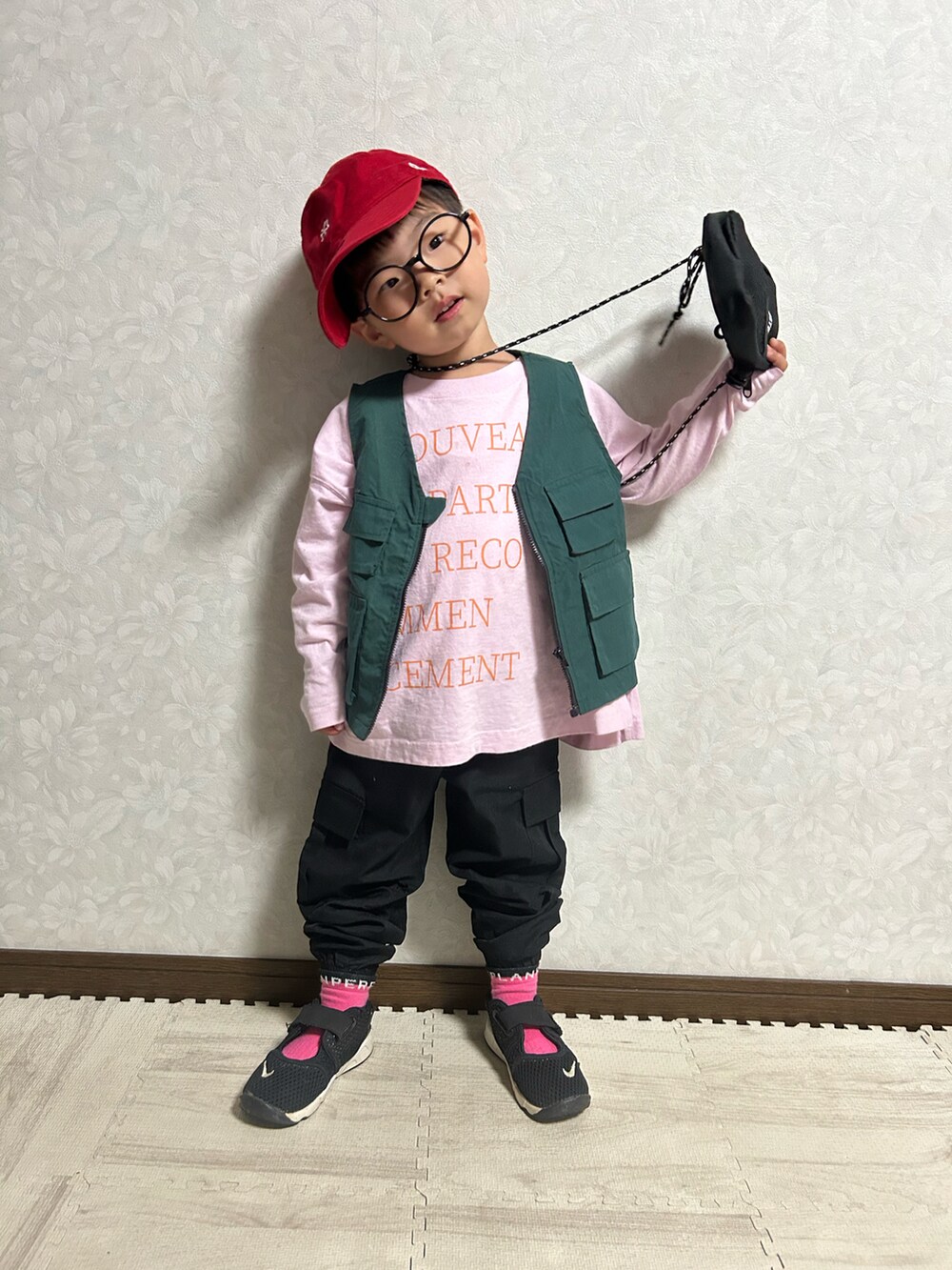 ピンク系のTシャツ/カットソー、グリーン系のベスト、ブラック系のショルダーバッグを着用したキッズの春コーディネートの2枚目の写真