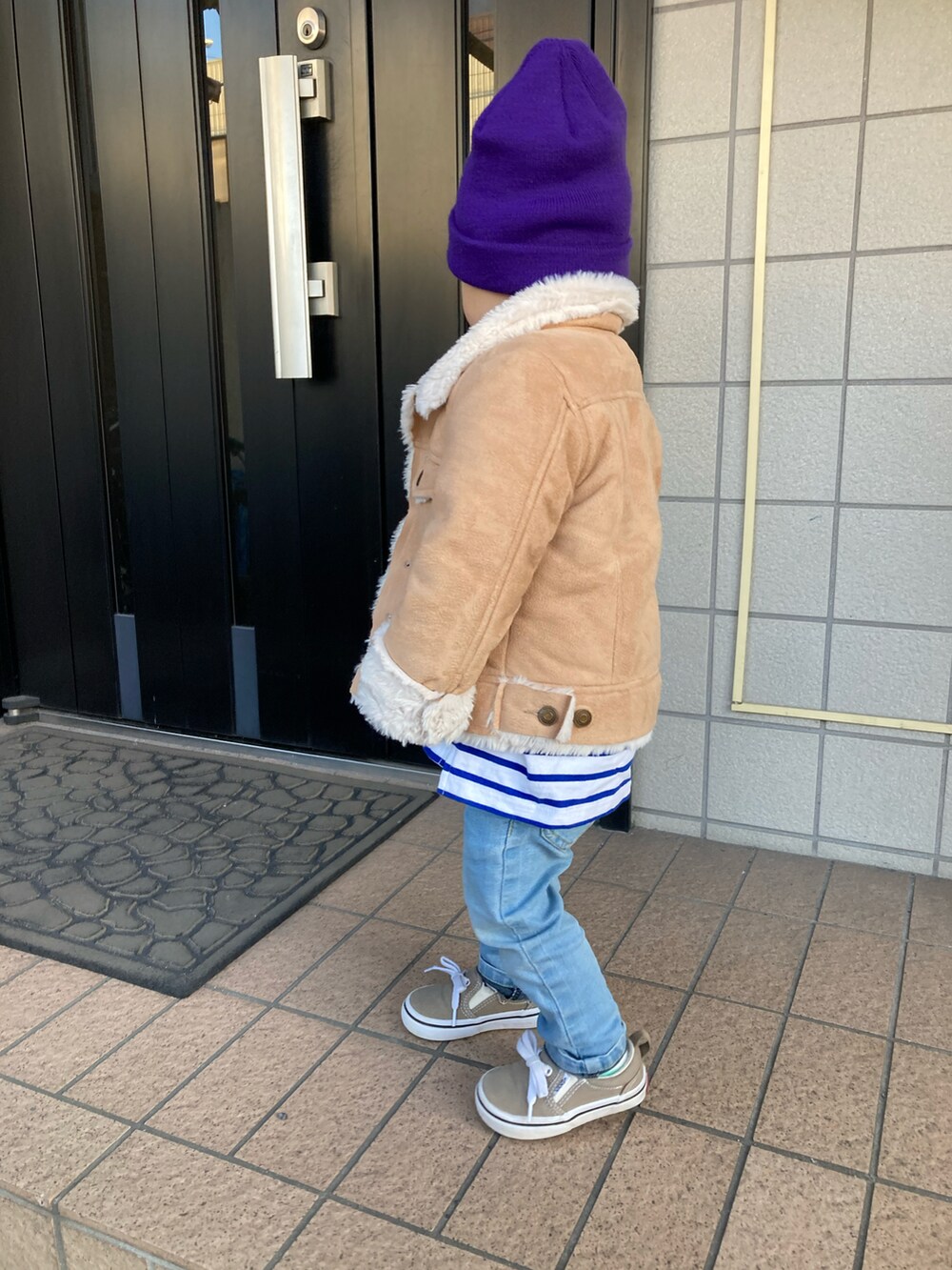 ベージュ系のジャケット/アウター、ブラウン系のスニーカー、ブルー系のキャップを着用したキッズの春コーディネートの2枚目の写真