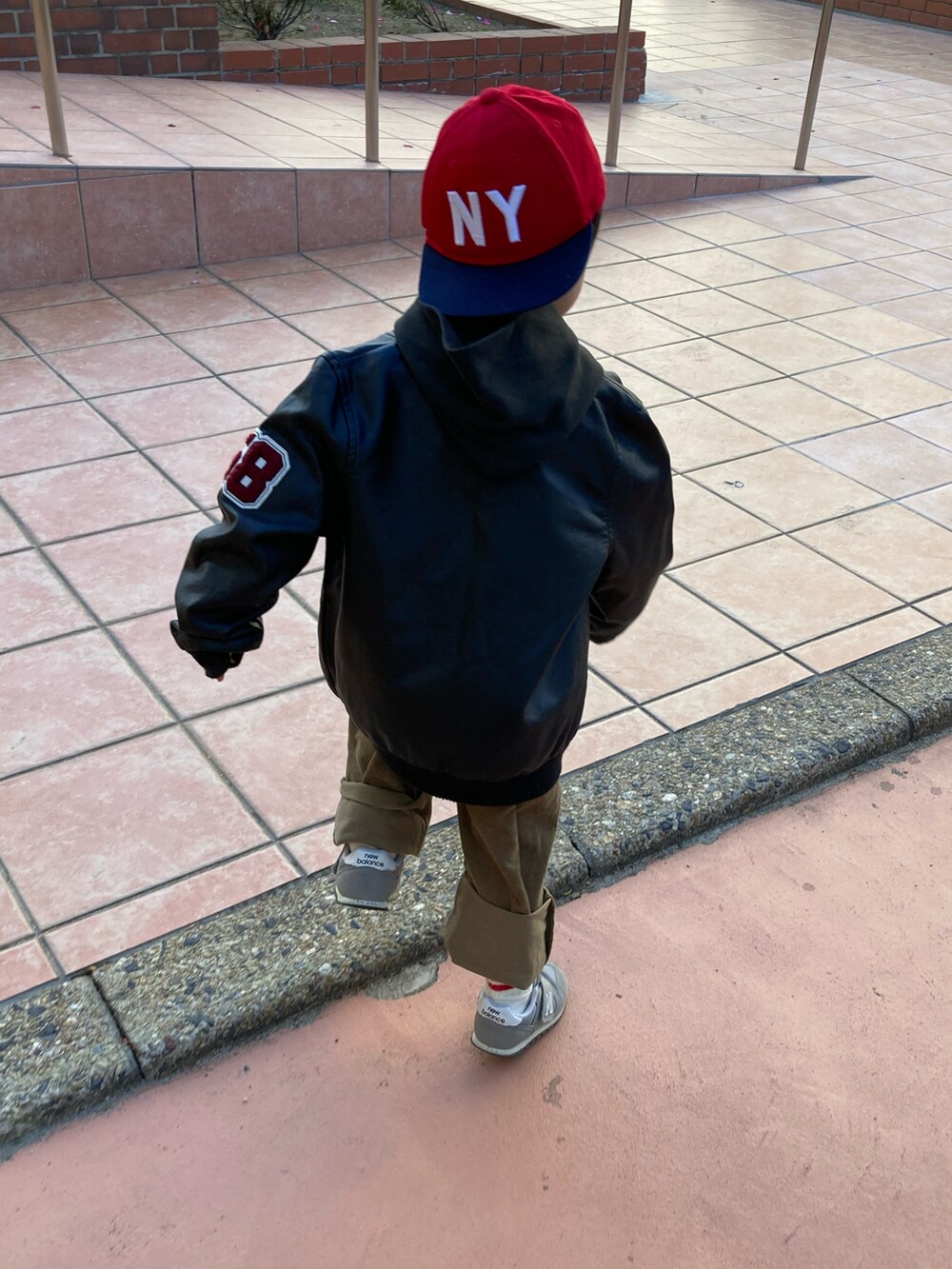 ブラック系のパーカー、グリーン系のサロペット/オーバーオール、グレー系のスニーカーを着用したキッズの冬コーディネートの4枚目の写真