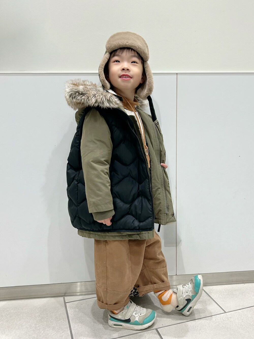 イエロー系のニット/セーター、ホワイト系のニット/セーター、グリーン系のモッズコートを着用したキッズの冬コーディネートの4枚目の写真