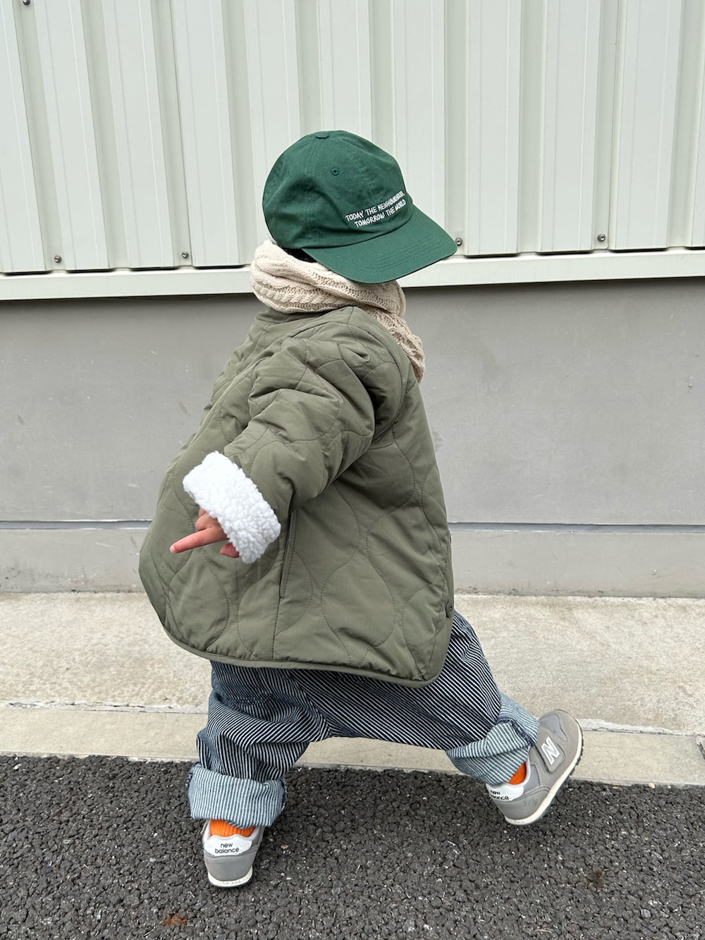 オレンジ系のスウェット、グリーン系のノーカラージャケット、ブルー系のデニムパンツを着用したキッズの冬コーディネートの3枚目の写真