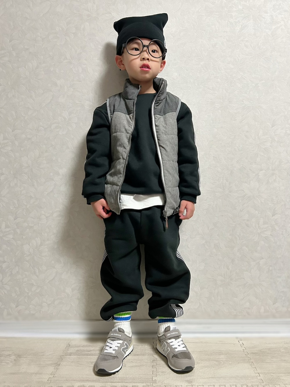 ホワイト系のTシャツ/カットソー、ブラック系のセットアップ、グレー系のダウンベストを着用したキッズの冬コーディネートの3枚目の写真