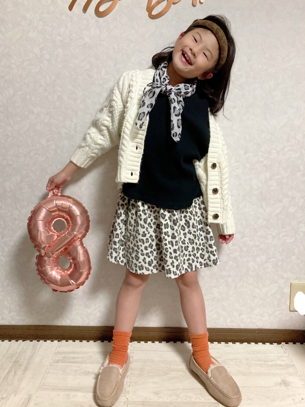 ブラック系のTシャツ/カットソー、ホワイト系のカーディガン/ボレロ、ベージュ系のスカートを着用したキッズの秋コーディネートの2枚目の写真