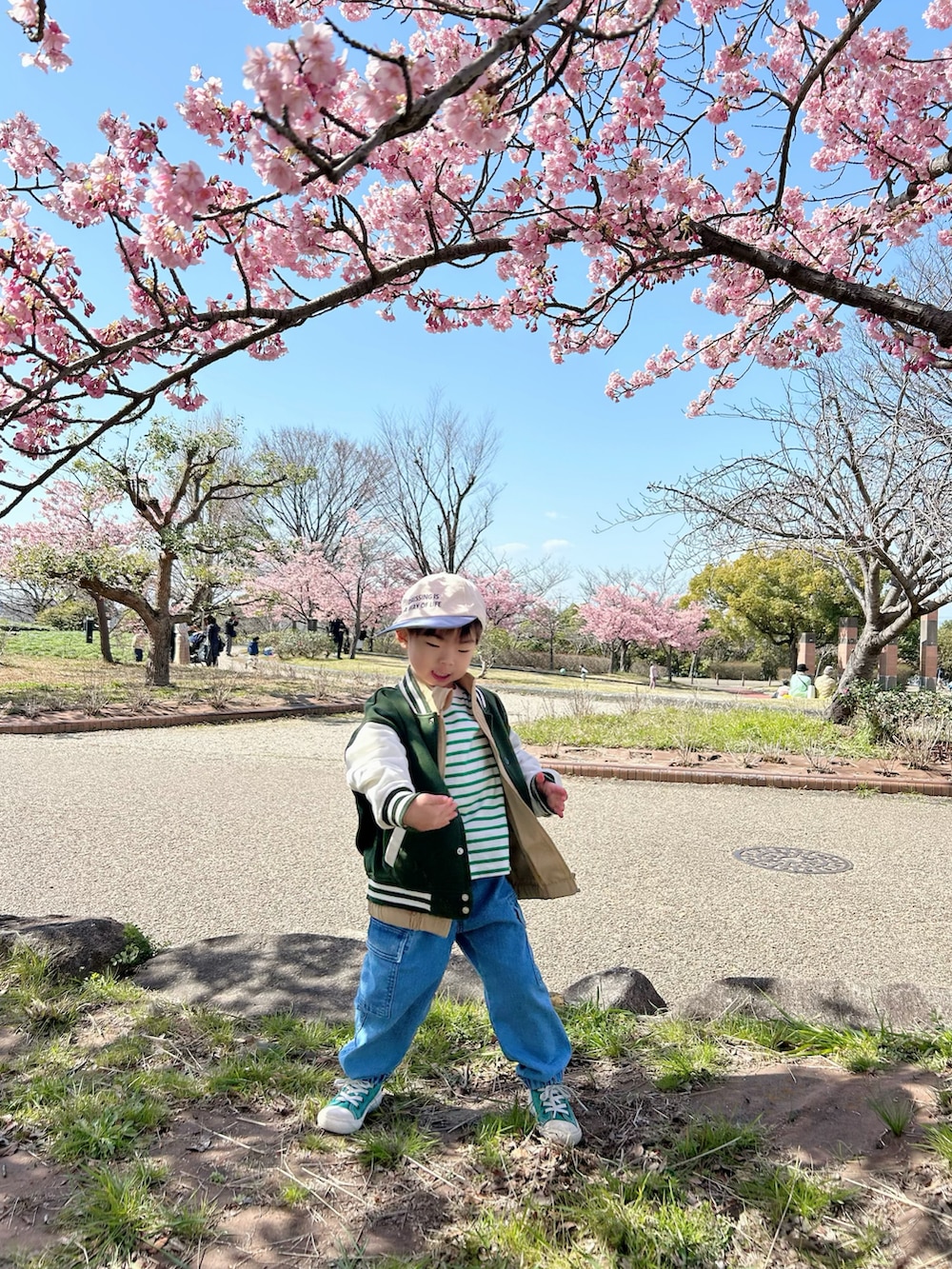 グリーン系のTシャツ/カットソー、ベージュ系のベスト、ブルー系のデニムパンツを着用したキッズの春コーディネートの2枚目の写真