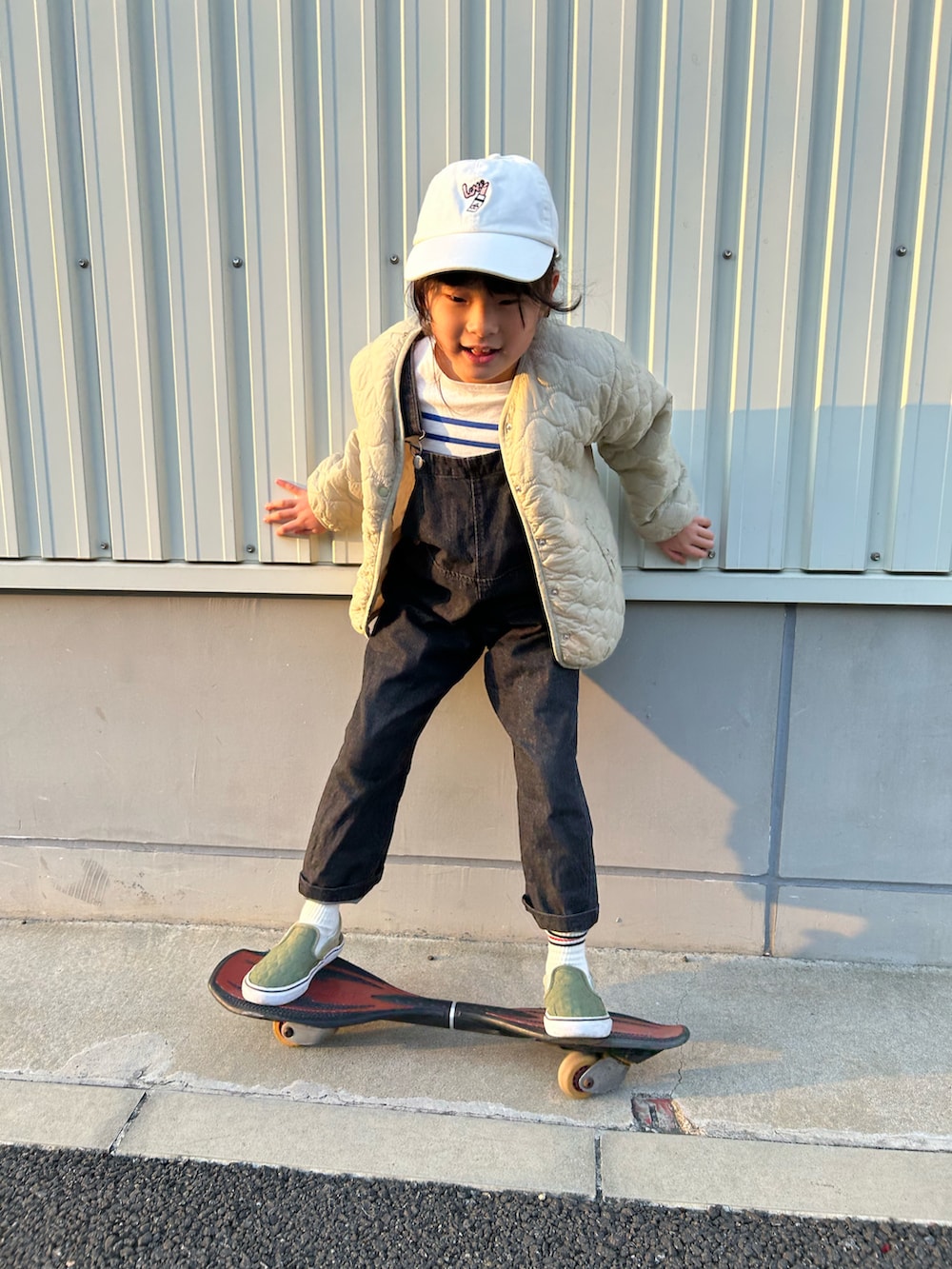 ブルー系のTシャツ/カットソー、ブラック系のサロペット/オーバーオール、グリーン系のブルゾンを着用したキッズの春コーディネートの4枚目の写真