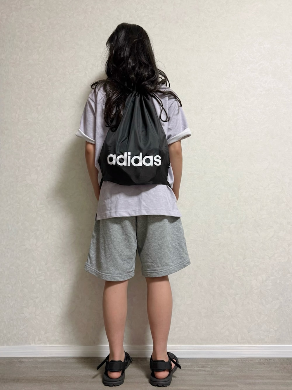 ブラック系のバックパック/リュック、ブラック系のサンダル、パープル系のTシャツ/カットソーを着用したキッズの夏コーディネートの4枚目の写真