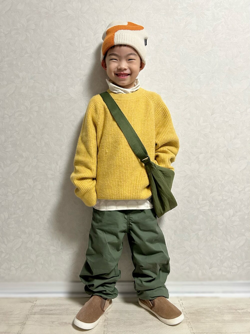 グレー系のTシャツ/カットソー、イエロー系のニット/セーター、グリーン系のショルダーバッグを着用したキッズの冬コーディネートの2枚目の写真