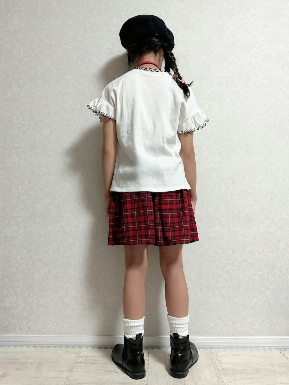 ブラック系のブーツ、ホワイト系のTシャツ/カットソー、レッド系のスカートを着用したキッズの夏コーディネートの3枚目の写真