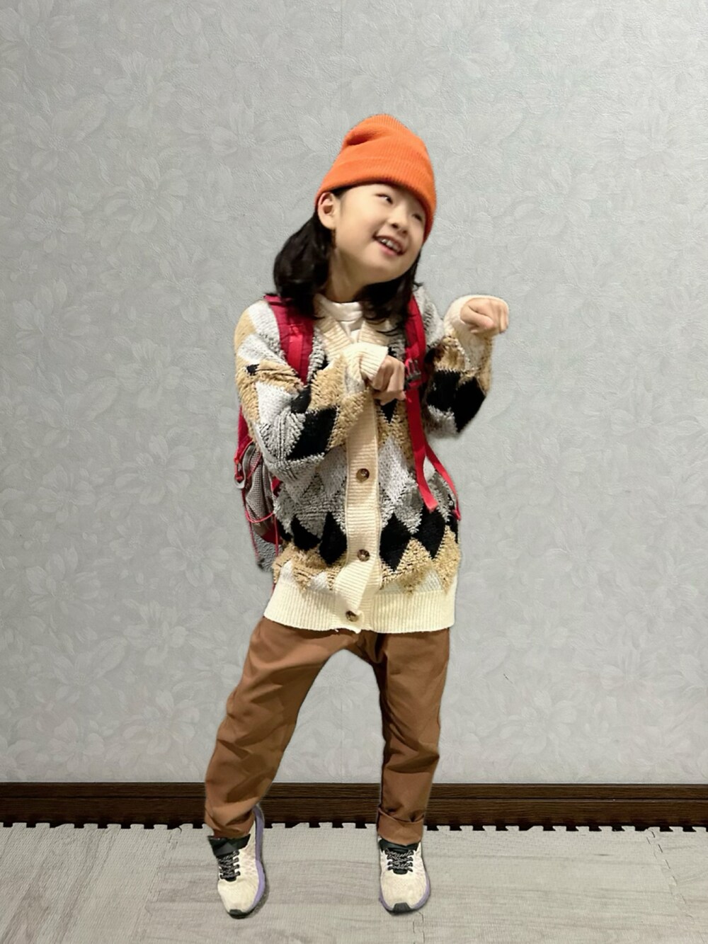 ホワイト系のTシャツ/カットソー、ベージュ系のカーディガン/ボレロ、レッド系のバックパック/リュックを着用したキッズの冬コーディネートの3枚目の写真