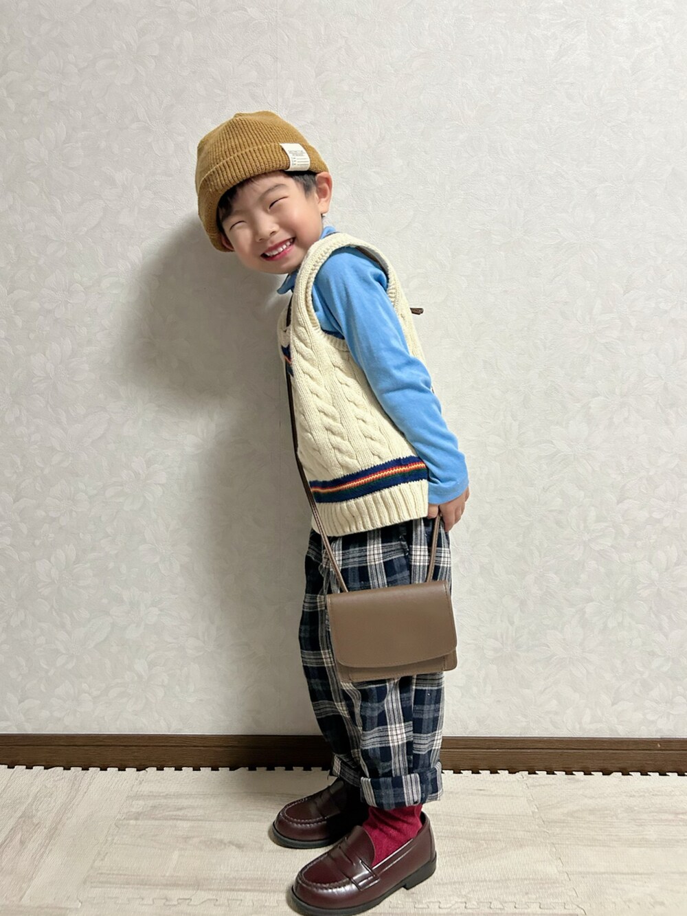 ブルー系のTシャツ/カットソー、ホワイト系のベスト、ブラウン系のショルダーバッグを着用したキッズの冬コーディネートの2枚目の写真