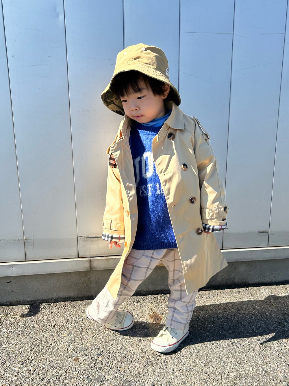 ベージュ系のトレンチコート、ブルー系のニット/セーター、ブルー系のTシャツ/カットソーを着用したキッズの冬コーディネートの2枚目の写真