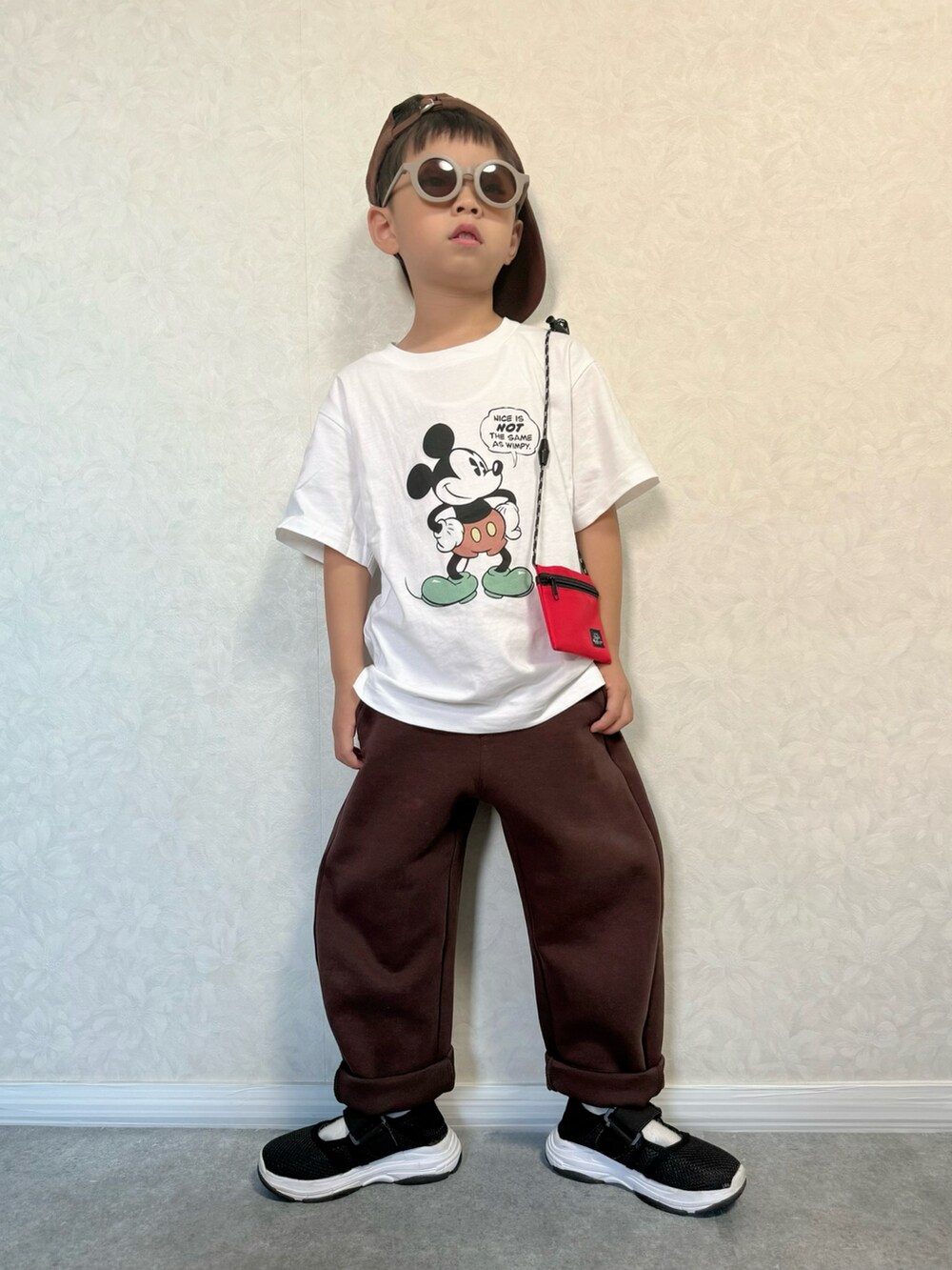 ブラック系のサンダル、ホワイト系のTシャツ/カットソー、ブラウン系のスウェットパンツを着用したキッズの夏コーディネートの2枚目の写真