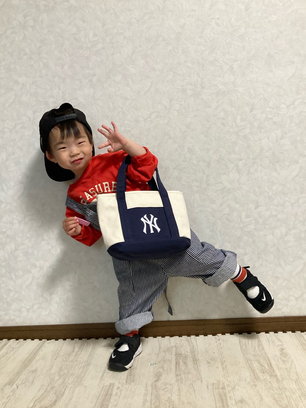 ホワイト系のショルダーバッグ、レッド系のTシャツ/カットソー、ブラック系のスニーカーを着用したキッズの春コーディネートの3枚目の写真