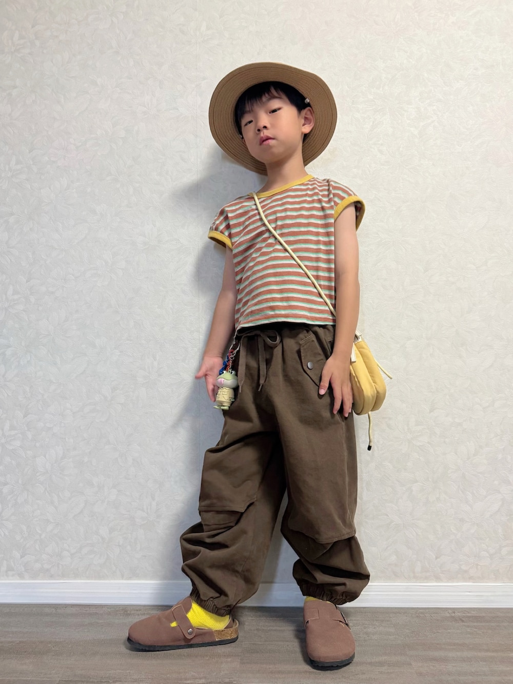 ブラウン系のTシャツ/カットソー、ブラウン系のカーゴパンツ、イエロー系のショルダーバッグを着用したキッズの夏コーディネートの4枚目の写真