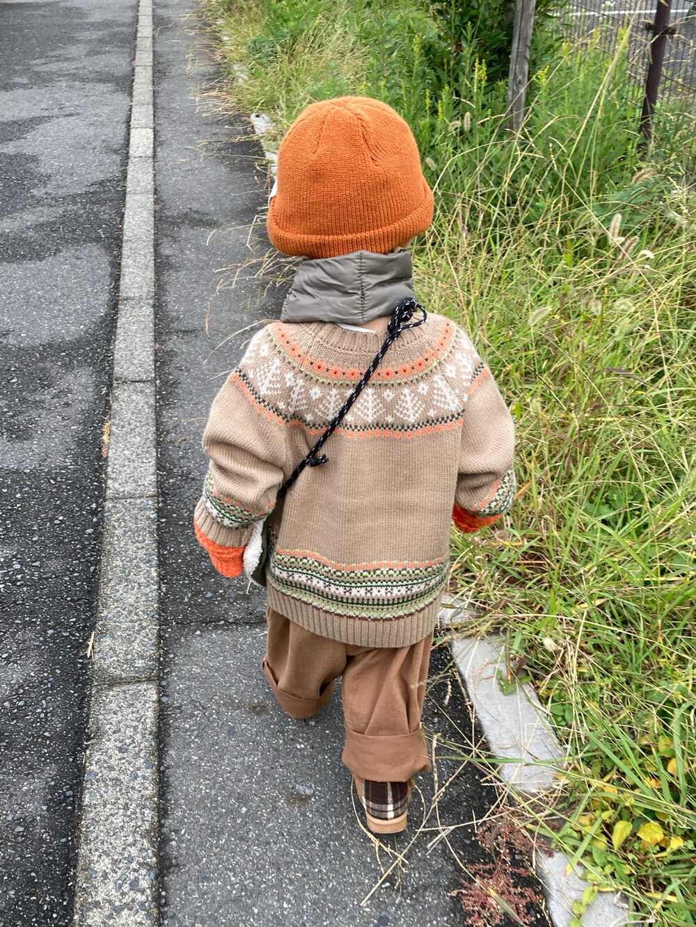 ベージュ系のニット/セーター、グリーン系のショルダーバッグ、ブラウン系のチノパンツを着用したキッズの秋コーディネートの4枚目の写真