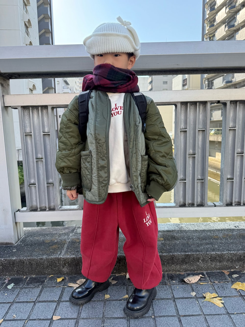 グリーン系のブルゾン、ブラック系のバックパック/リュック、レッド系のセットアップを着用したキッズの冬コーディネートの3枚目の写真