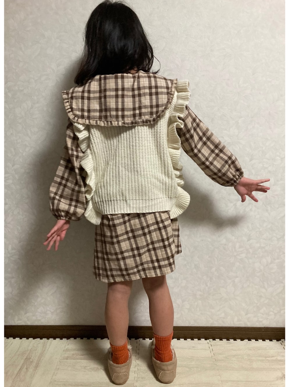 ブラウン系のシャツワンピース、ベージュ系のベスト、グリーン系のスカートを着用したキッズの秋コーディネートの3枚目の写真