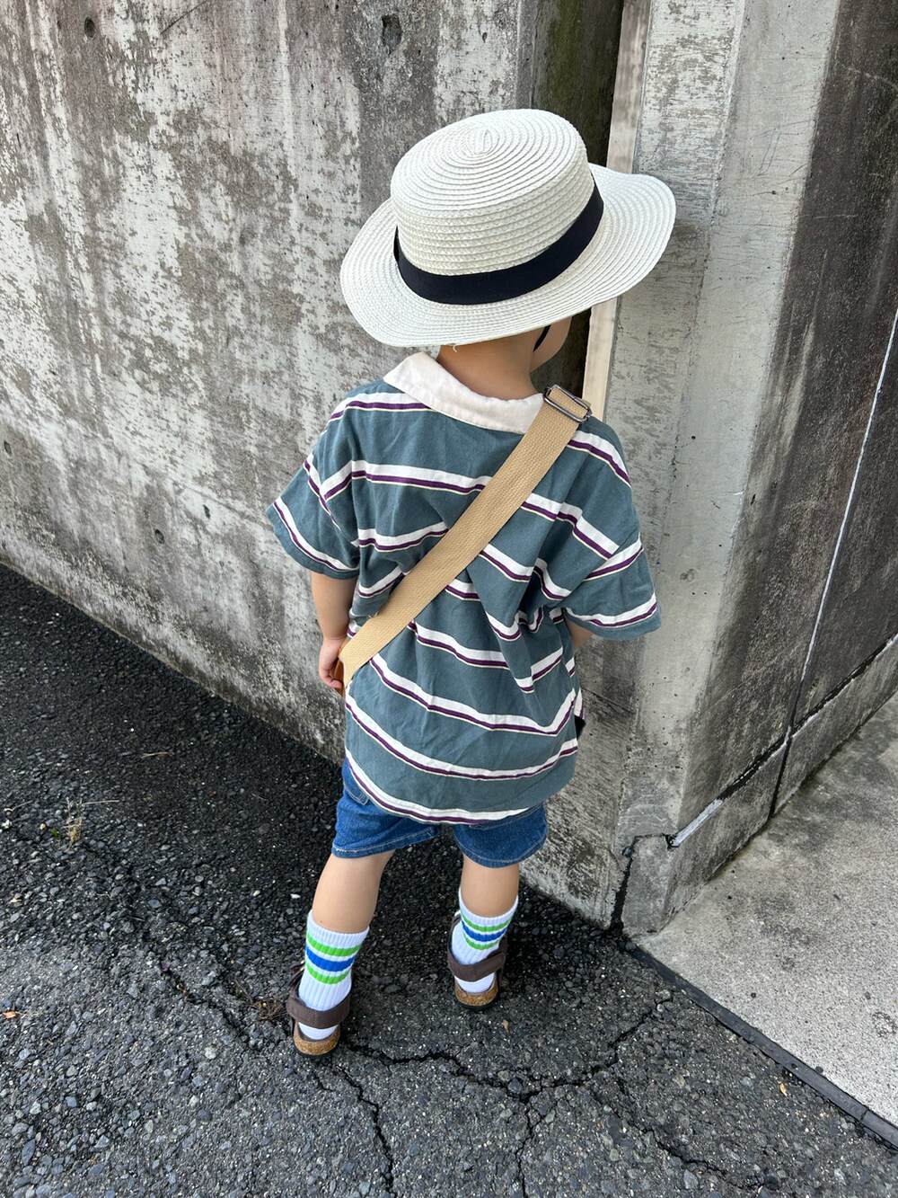 グリーン系のポロシャツ、ブラウン系のショルダーバッグ、ブルー系のデニムパンツを着用したキッズの夏コーディネートの3枚目の写真
