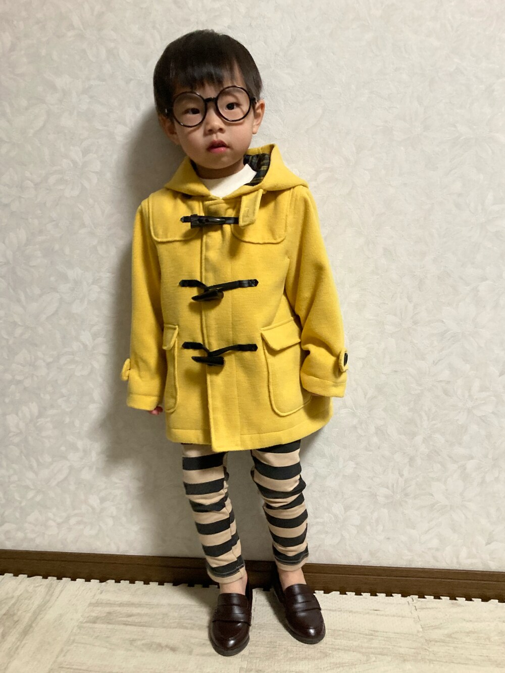 ホワイト系のニット/セーター、イエロー系のダッフルコート、ブラック系のその他パンツを着用したキッズの冬コーディネートの2枚目の写真